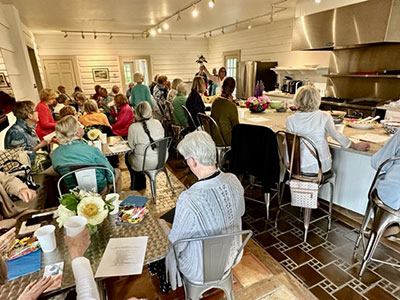 Large group of people seated at tables and a bar in a kitchen