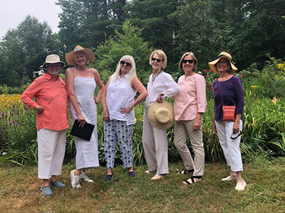 Group of women looking at the camera in front of a flower bed
