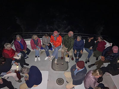 Group of seated people on a boat as seen from an upper deck